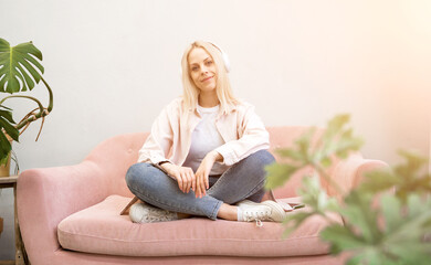 Attractive young blonde woman lying on the couch listeting to music. Relaxing concept 
