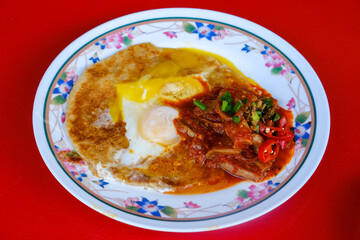 A picture of "roti sarang burung sambal sotong" serve on the table. Paratha with two sunrise eggs at the middle.