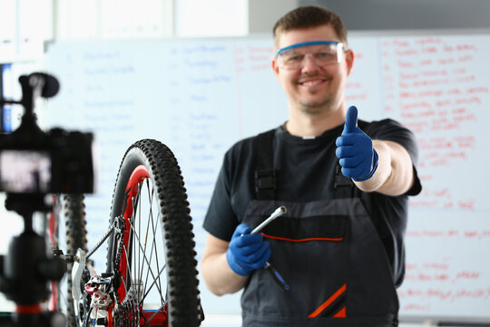Bicycle repairman in workshop holding thumbs up