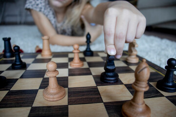 selective focus on a child's hand holding a chess piece, games and education of children at home during a pandemic