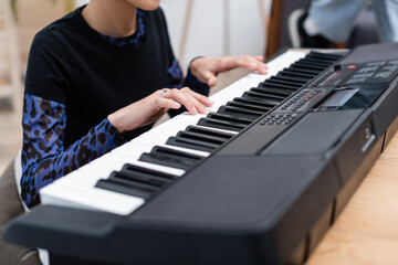 Obraz premium Cropped view of african american woman playing blurred synthesizer at home.