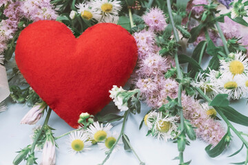 Red soft heart on the background of a bouquet of wild flowers.