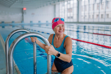 Active senior woman swimmer using ladder to get to swimming pool. © Halfpoint
