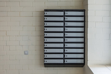 Many new grey mailboxes attached to wall in multi storey apartment building