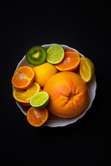 citrus on a plate. lemon. grapefruit. orange. kiwi. lime on a black background