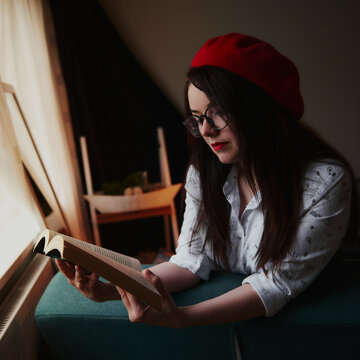 a girl with dark long hair in a red beret and a white blouse, retro style. Indoor soft light