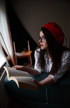 a girl with dark long hair in a red beret and a white blouse, retro style. Indoor soft light