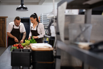Chef teaching how to cook, cutting vegetables indoors in commercial kitchen.