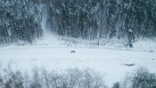 4K. Road in the frozen winter forest with driving car. Aerial panoramic view. 