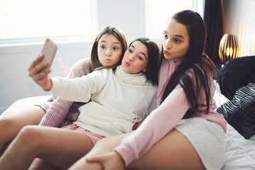 teen friends girls with smartphone taking selfie at home