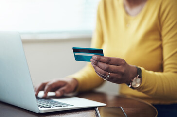 Fototapeta premium Saturdays are self-spoil days. Cropped shot of an unrecognizable woman sitting alone at home and using her laptop for online shopping.