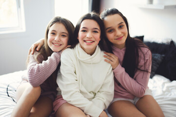 Obraz premium Three excited teenager girls having fun together, enjoying laze leisure time at home