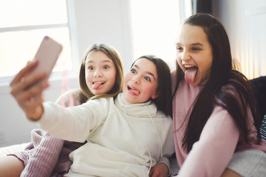teen friends girls with smartphone taking selfie at home