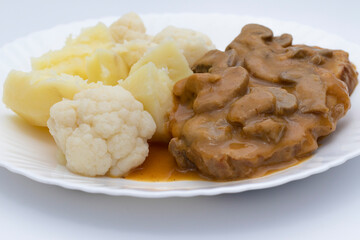 A meat dish with mushroom sauce, accompanied by potatoes with cauliflower. Delicious food concept.