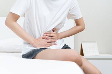 Obraz na płótnie Canvas person feeling stomach pain menstruation on the bed.