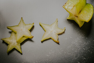 Preparing a fresh star fruit sliced in a dark background