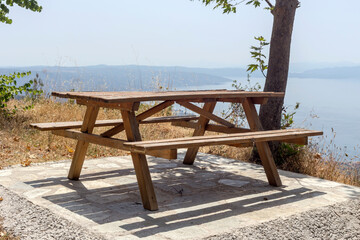 Fototapeta na wymiar The benches with a table overlooking the sea and mountains in the distance (Greece, Pelion)