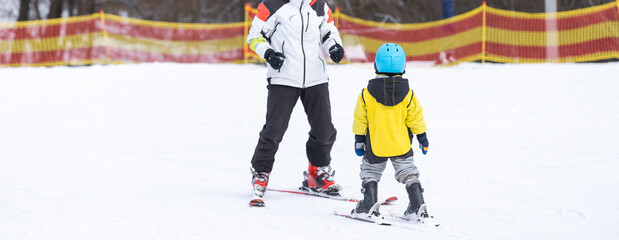 Instructor and little child skiing. toddler kid with safety helmet. Ski lesson for young children....