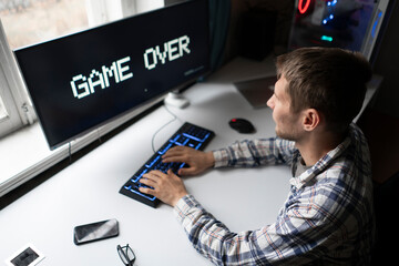 male gamer loosing a video game, game over text on the screen