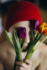 Boy face hidden with colorful flowers bouquet. Tulips bouquet