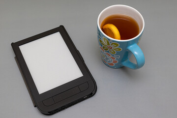 an e-book lies on the surface next to a mug of tea