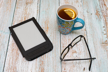 a table on which lies an electronic book, a mug and glasses with a diopter