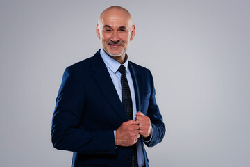 Middle aged businessman wearing suit and tie while standing at isolated grey background