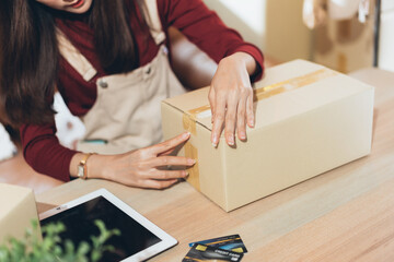 SME small business woman packing and taping carton box. entrepreneur or shop owner working at home. Preparing for delivery, online e-commerce