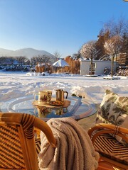 Piknik zimowy pod ciepłym kocem z kubkiem gorącej kawy w pięknym zimowym ogrodzie - obrazy, fototapety, plakaty