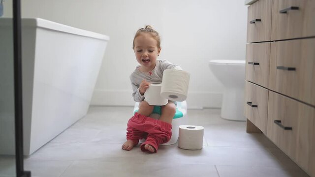An Adorable young baby child sitting and learning how to use the toilet 
