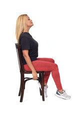 Fototapeta premium side view of a woman dressed in sportswear sitting on a chair on white background