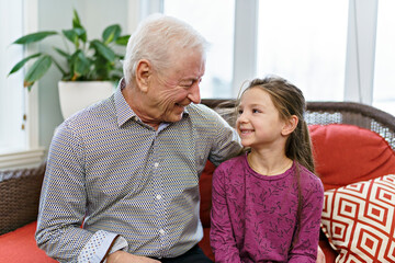 grandpa and little granddaughter having great time on sofa at home