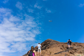A group of hikers watch as an airliner passes overhead at low altitude.