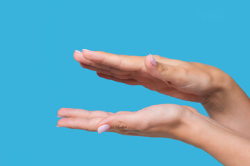 Closeup view stock photo of two manicured female hands making clapping gesture or holding something virtual and invisible between her flat empty palms