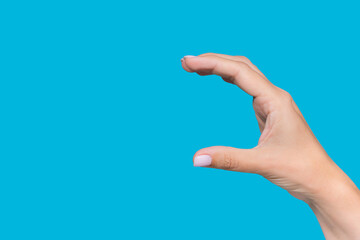 Closeup view stock photography  of beautiful white manicured female hand holding virtual invisible object of big size with help of her fingers isolated on blue background