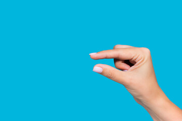 Closeup view stock photography  of beautiful white manicured female hand showing small size of virtual invisible object with help of two fingers isolated on blue background - Powered by Adobe