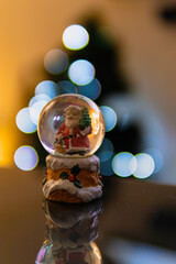 Santa Christmas ball with snow inside and christmas lights in the background, beautiful bokeh balls