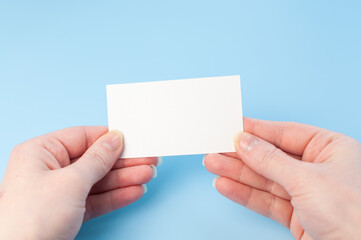 Female hands with a blank card isolated on blue background. Hands with empty white card. Mock up