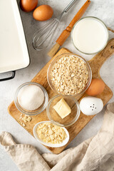  Ingredients for pudding or oatmeal pie on a light gray culinary background. Eggs, cereals, almonds, sugar, milk and butter on the kitchen table. Top view