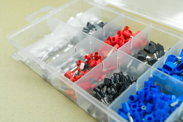 A set of colored crimp terminals for electrical wires. Crimping sleeves of different sizes. Plastic spare parts box for electrician. Toolbox. Selective focus