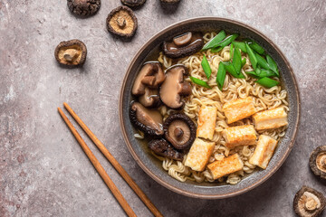 Asian vegetarian ramen noodle soup close-up with roasted tofu cheese and shiitake mushrooms in a...