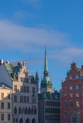Obraz premium The tower of the German church Tyska Kyrkan between old 1700s building in the old town Gamla Stan a sunny winter day in Stockholm