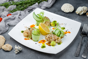 grilled scallop, sliced with vegetables and lemon on grey table