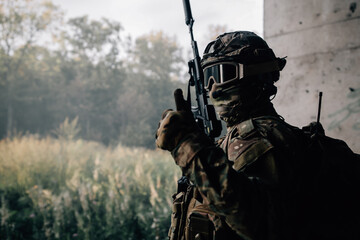 Soldier in camouflage uniform with a rifle points his finger cool