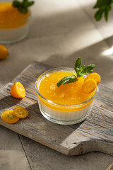 Orange Panna Cotta, a Creamy Italian Pudding with a tropical fruit Gelatin Layer and mint, on wooden Cutting Board. Beautiful summer day. Copy space.