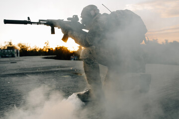 Soldier man sitting on concrete shooting at opponents from a rifle military operations are underway