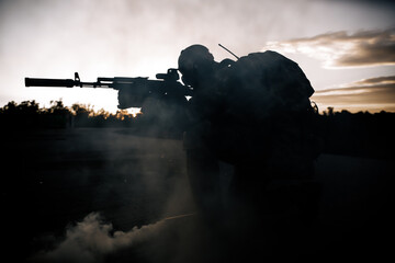 Military man in a gas mask sitting on concrete aiming at a sniper rifle