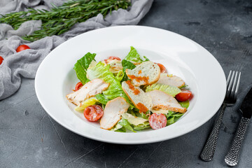 Salad caesar with chicken on white plate on grey table