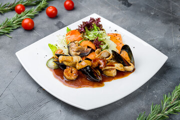 Salad with seafood on white plate on grey table
