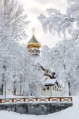 Naklejka premium The church in winter is a year. Orthodox church with gilded dome and cross against the background of a winter forest